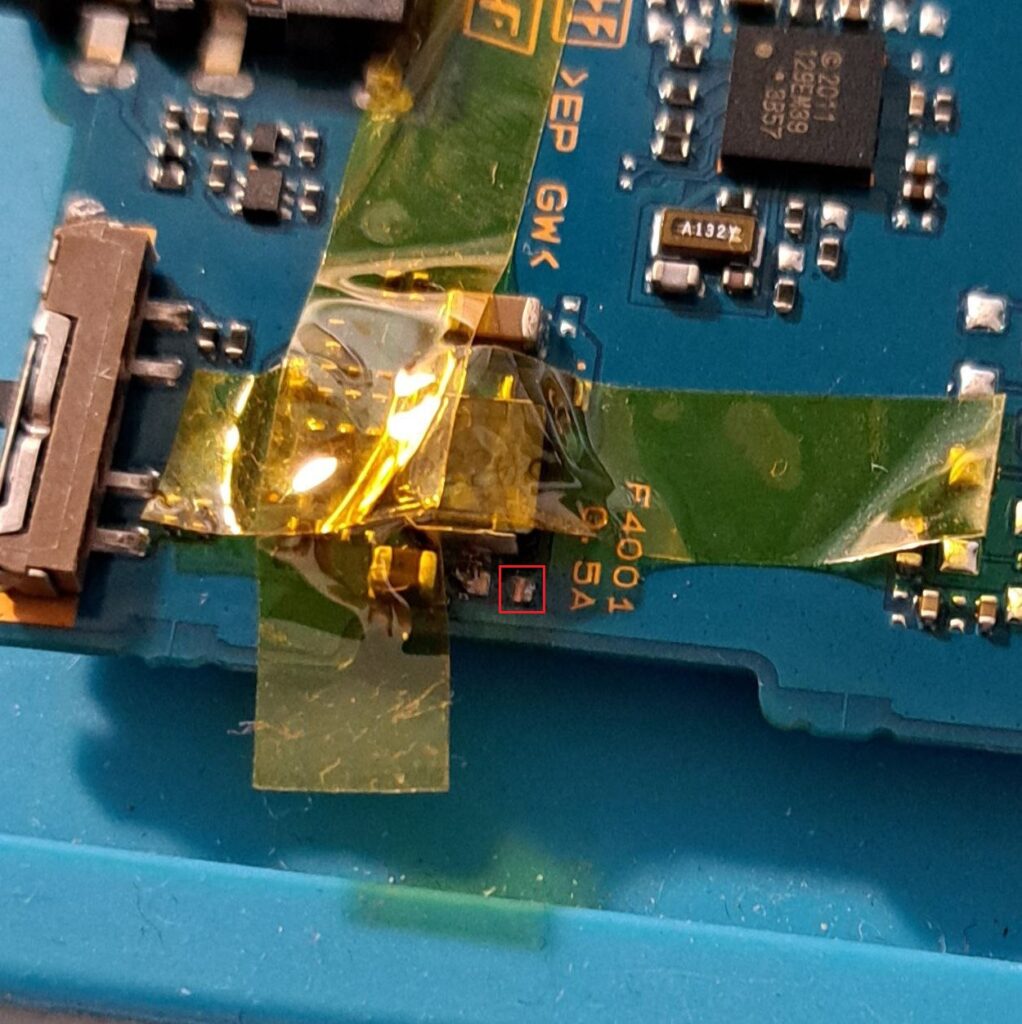 Nahaufnahme des Motherboards. Teile sind mit Kapton-Tape abgeklebt und die Sicherung ist mit einem roten Kästchen markiert.