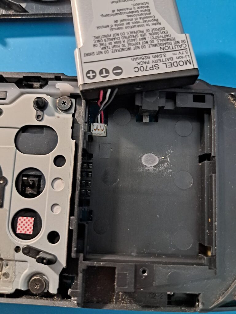 Akku der PSP Street wurde aus der Halterung gehoben; der Anschluss zum Motherboard ist zu sehen