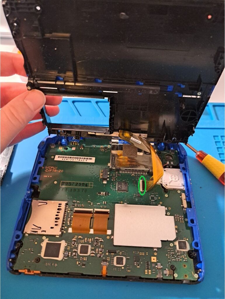 Rückseite des Motherboards eines 2DS, das Flachbandkabel der Außenkamera ist markiert