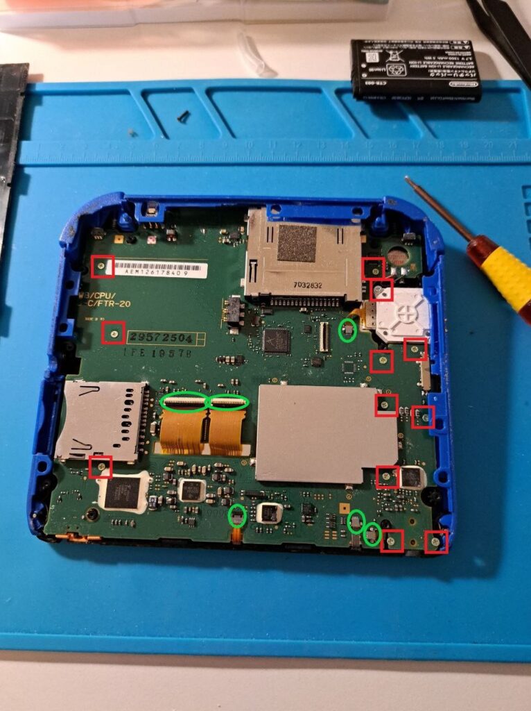 Motherboardrückseite eines 2DS, Schrauben und Flachbandkabel sind markiert